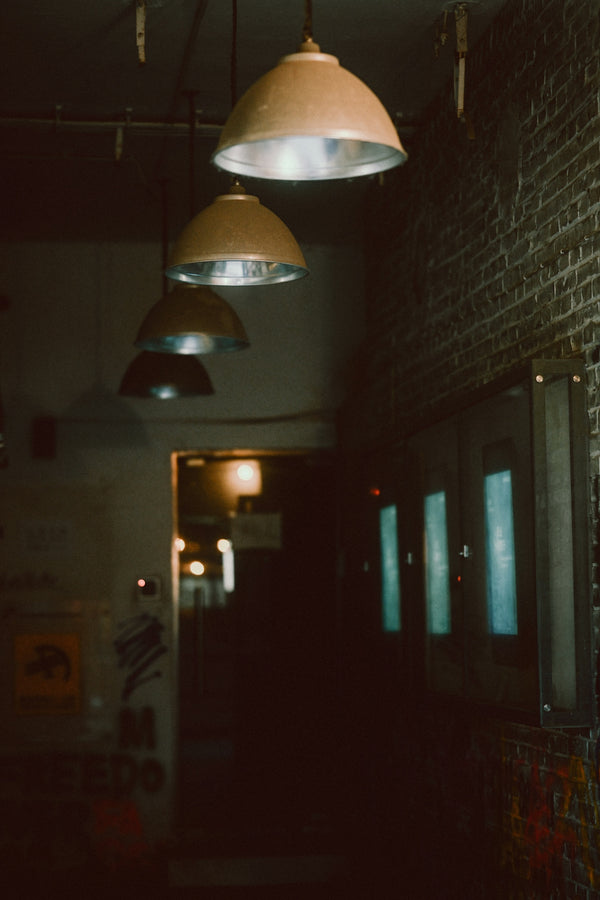 Pendant lights hanging in a row above a dark brick hallway